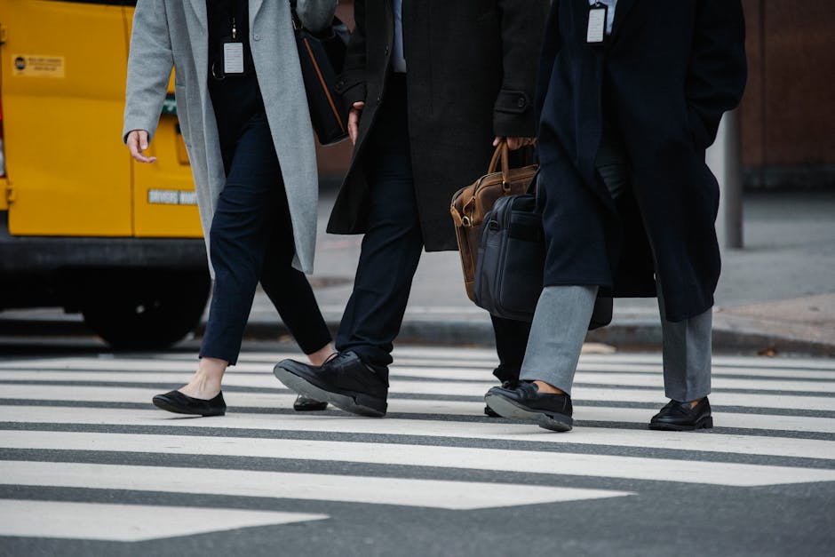 Business professionals in coats cross a city crosswalk, highlighting urban lifestyle.
