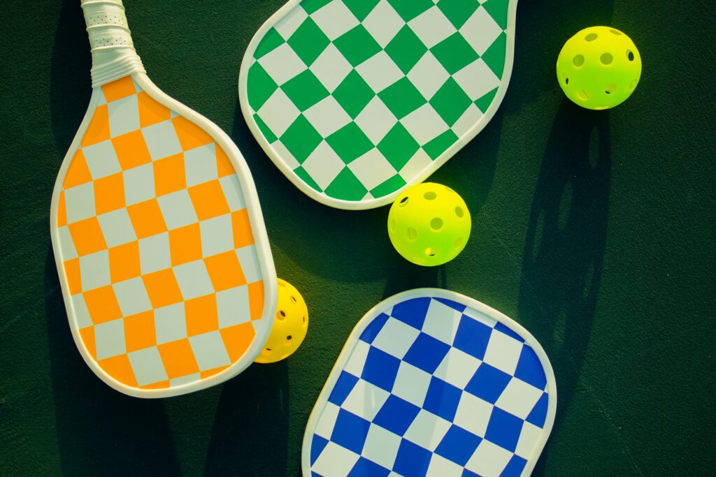 Vibrant pickleball paddles and balls arranged on a sunny sports court.