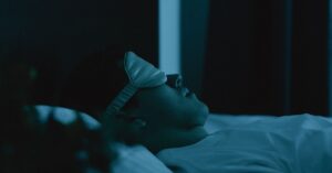 Adult resting peacefully in bed wearing a sleep mask, captured in a serene nighttime setting.