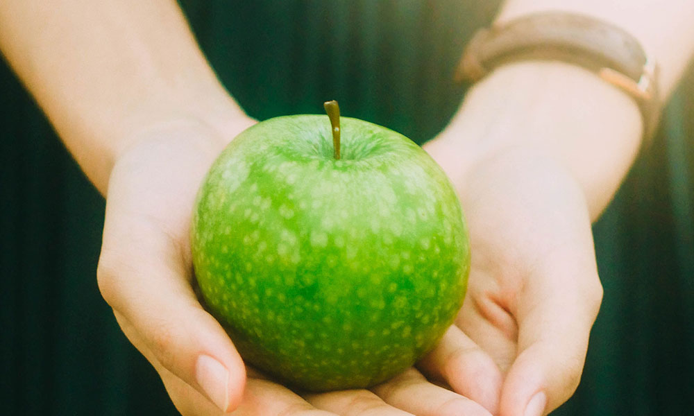female hands hold a green apple