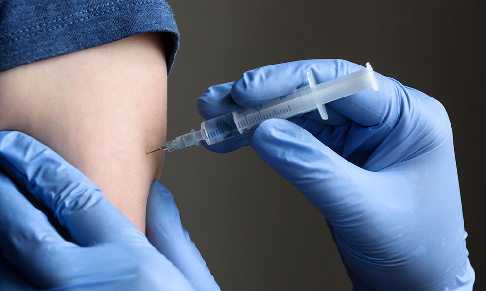 COVID-19 vaccine shot, doctor holds syringe and makes injection to patient